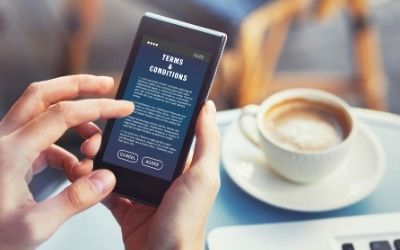 man with smart phone with terms and conditions on it and coffee cup