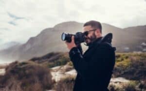 photographer wearing black jacket with hills behind