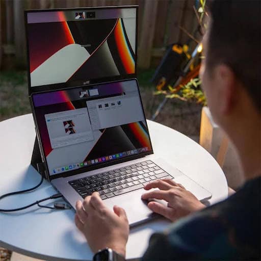 Entrepreneur presenting business pitch using a portable monitor in a cafe
